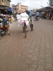 Un cycliste transportant des sacs de farine de blé, au marché Ouando, Porto Novo, Bénin